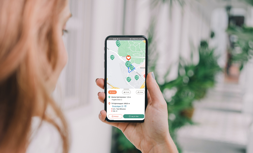 Kvinna tittar på kartan för tillgänliga hjärtstartare i närheten av hjärtstop i appen Sms-livräddare.