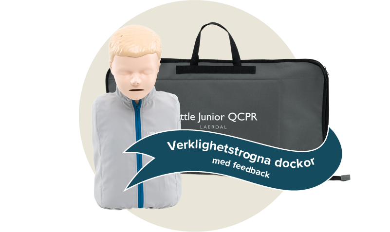 Little Junior QCPR docka med en grå och blå jacka. En grå väska från Laerdal. Etikett: Verklighetstrogna dockor med feedback