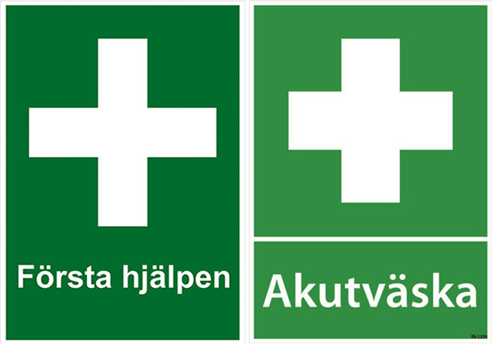 Första hjälpen skyltar, två gröna skyltar båda med ett vitt kors. På står det första hjälpen och akutväska